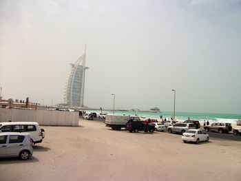 Cars on beach against sky in city