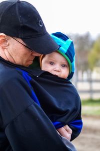 Portrait of cute baby boy carried by grandfather outdoors