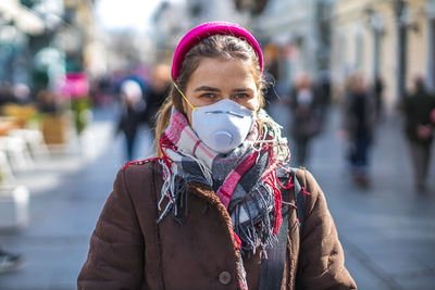 Portrait of woman wearing mask on street in city during winter