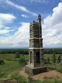 Built structure on landscape against cloudy sky