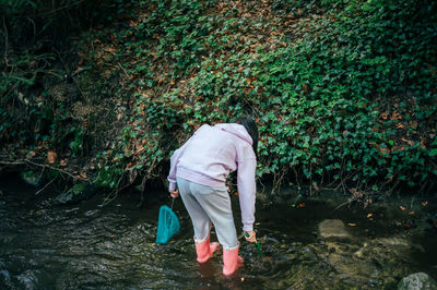 One girl playing in the forest. asian child fishing with a net to discover nature. 