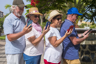 Side view of senior people using smart phone while standing at park