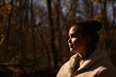 Portrait of young woman looking away in forest