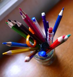 High angle view of colored pencils on desk by window
