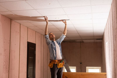 Full length of young woman standing against wall