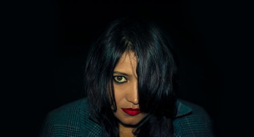 Close-up portrait of a beautiful young woman over black background