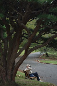 Woman sitting on tree trunk