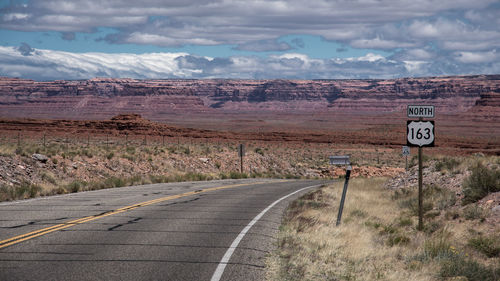 Road sign on landscape against sky