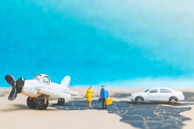 Toy car on beach against blue sky