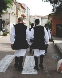 Rear view of two men standing in front of building