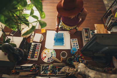 High angle view of artist painting on table while standing at home
