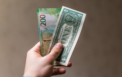 Close-up of man holding money against brown background