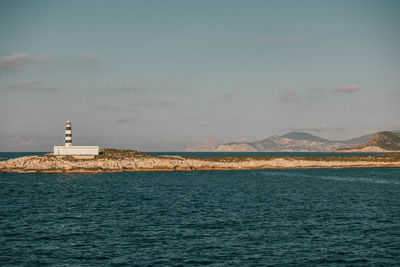 Lighthouse by sea against sky