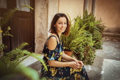 Portrait of young woman smiling while sitting outside house