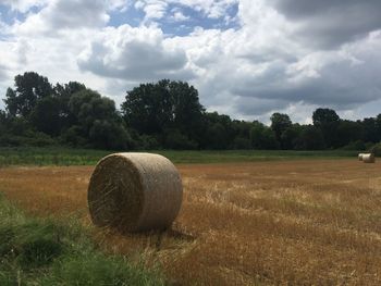 Hay bales on field against sky