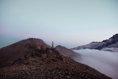 Mid distance view of man standing on mountain against sky