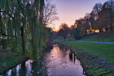 Footpath by lake against sky during sunset