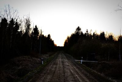 Road amidst trees against sky during sunset