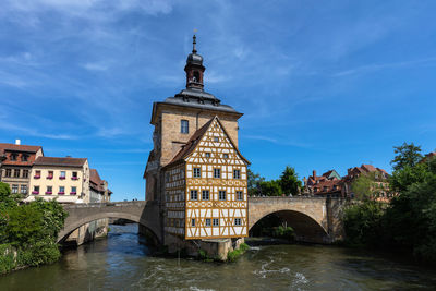 Arch bridge over river amidst buildings against sky