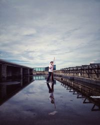 Man walking on bridge over sea against sky