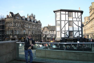 People standing on bridge against buildings in city