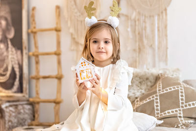 A girl  with a headband  of deer horns and a christmas toy in her hands.christmas holidays