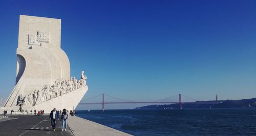 Monument to the discoveries on promenade by tagus river against clear blue sky