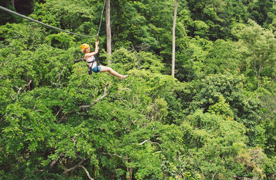 Full length of woman zip lining in forest