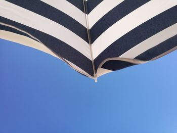 Low angle view of umbrella against clear blue sky