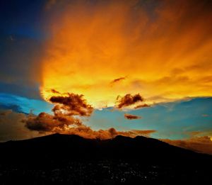 Silhouette landscape against dramatic sky during sunset