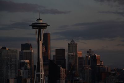 Skyscrapers in city against sky at sunset