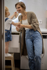 Daughter brushing teeth of mother at home