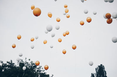 Low angle view of gold and white balloons against sky