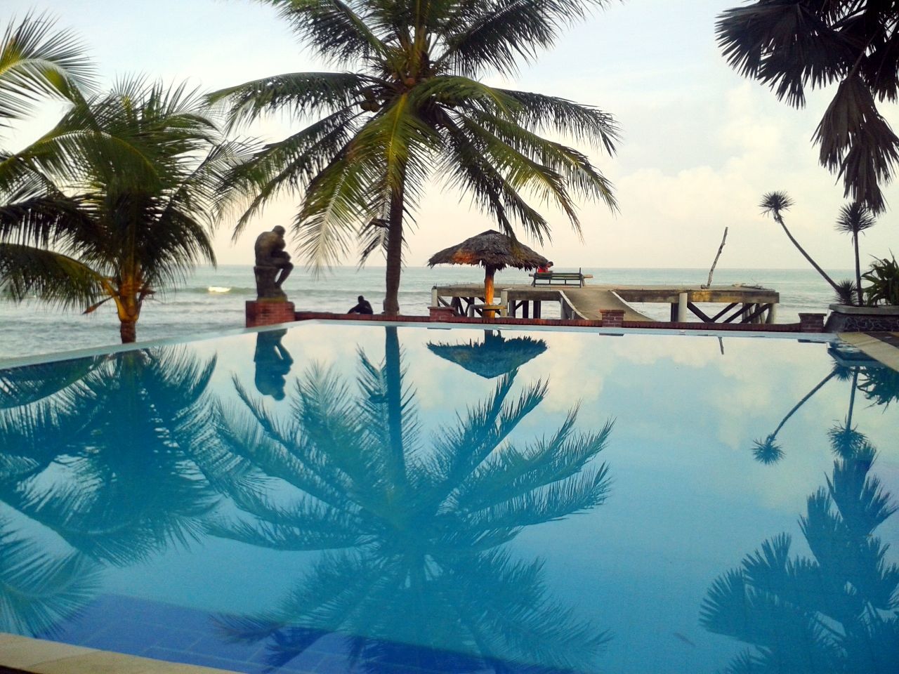 palm tree, sea, tree, beach, water, sky, swimming pool, horizon over water, tranquility, tranquil scene, shore, coconut palm tree, scenics, nature, beauty in nature, vacations, tree trunk, sand, tourist resort, growth