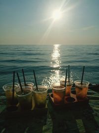 View of drink on table by sea against sky
