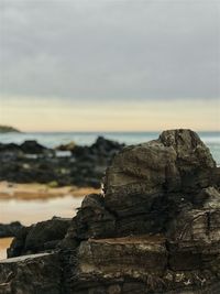 Rock formations on shore against sky