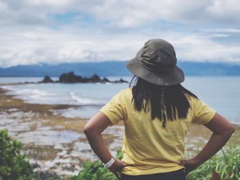 Woman standing at beach against sky