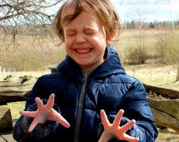 Close-up of boy with eyes closed clenching teeth while standing on field