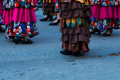 Low section of people wearing sandals and dress while walking on road