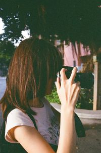 Rear view of woman holding camera