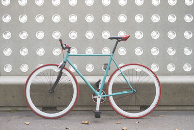 Bicycle parked on wall by street