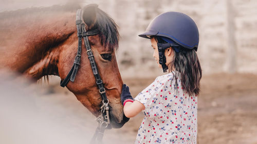 Side view of girl with horse outdoors