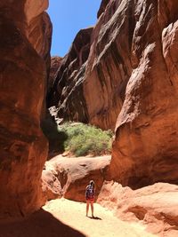 Rear view of woman standing by rock formation