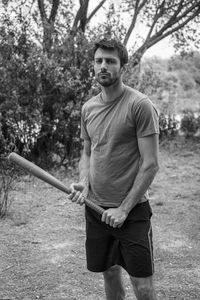 Portrait of young man standing against trees