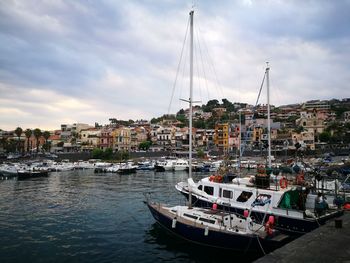 Boats in marina at harbor against sky