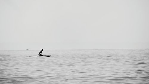 Man paddleboarding on sea against clear sky