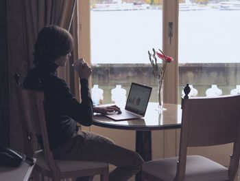 Man having coffee while using laptop at home