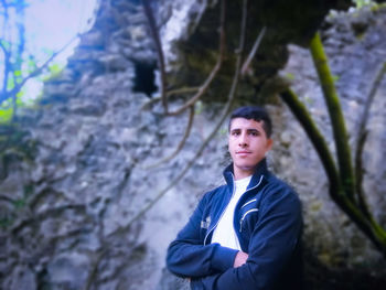 Portrait of young man standing against rock