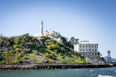 Built structure by sea against clear blue sky