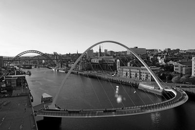 Bridge over river in city against clear sky